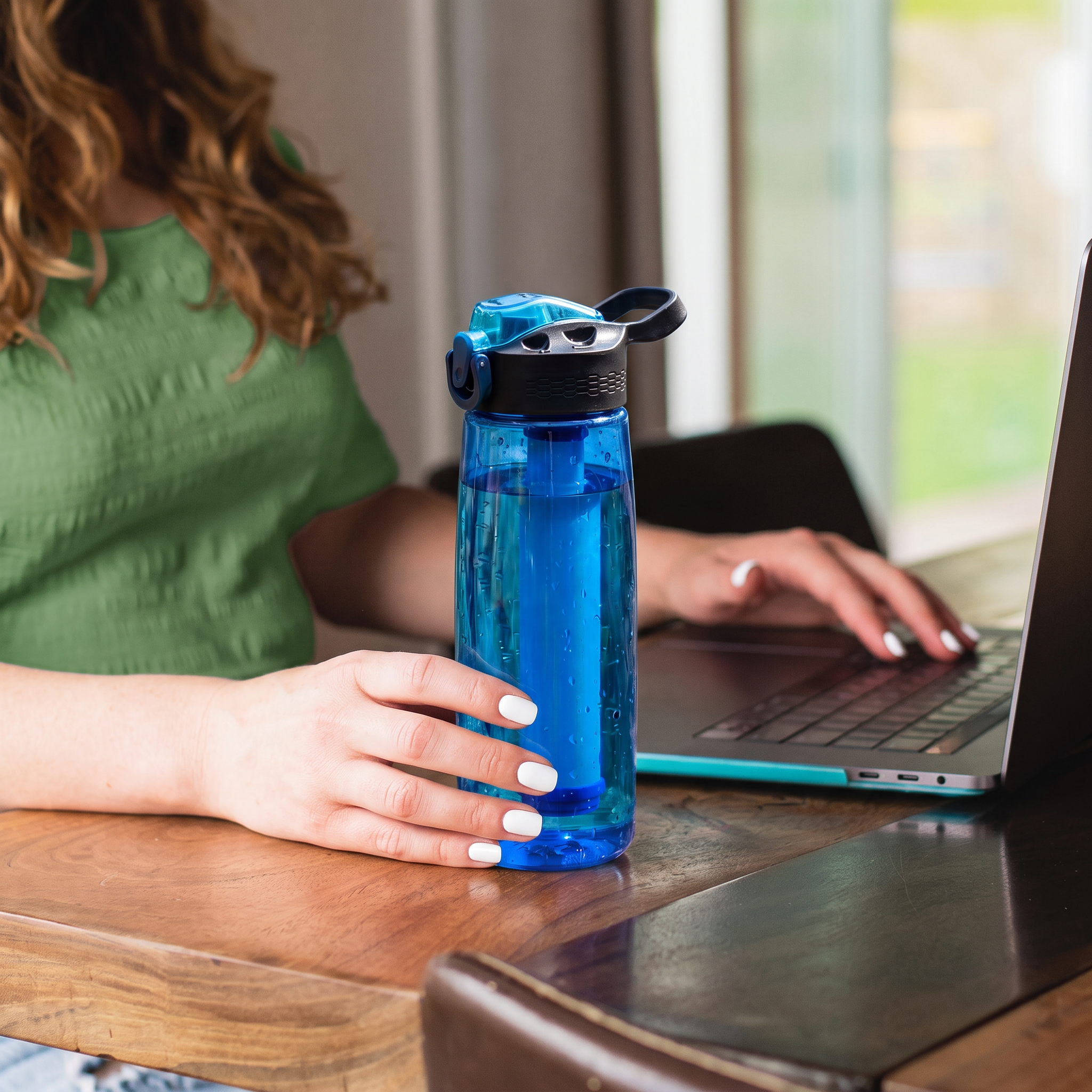 Femme travaillant à son bureau avec sa gourde filtrante Lebeau